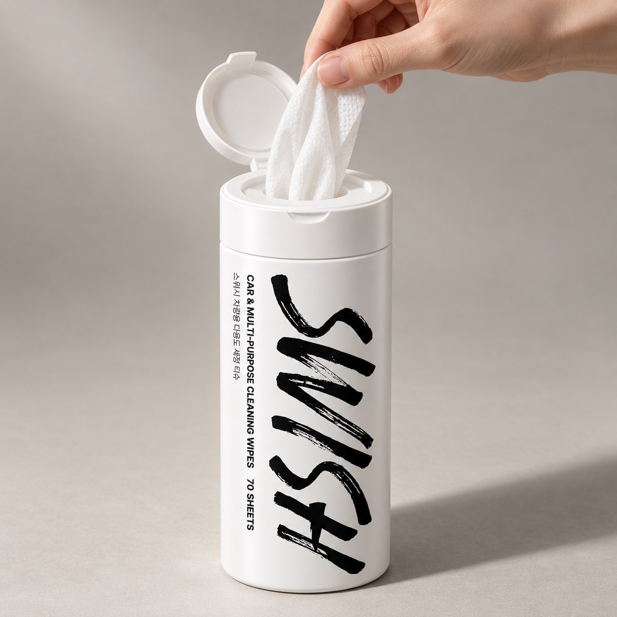 A hand pulling a cleaning wipe from an open SWISH canister